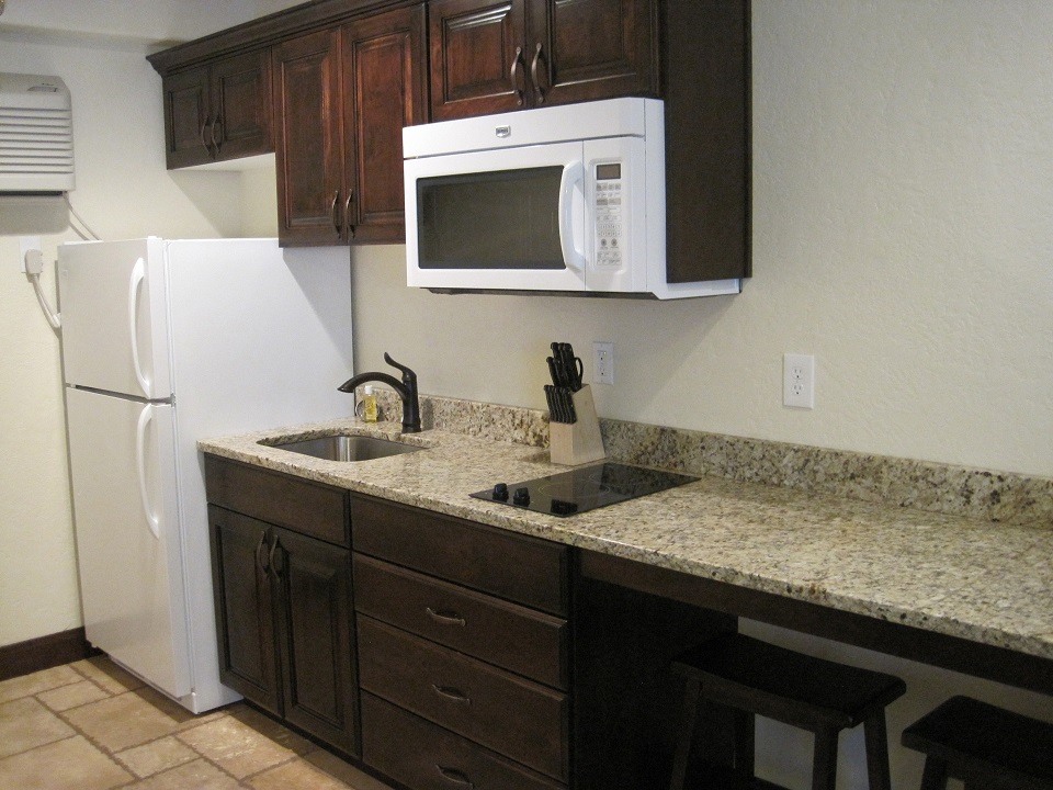 A photo of a kitchen with a granite counter and wooden cupboards